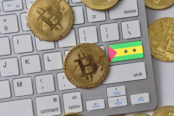 national flag of sao tome and principe on the keyboard with bitcoin coins on a grey background.