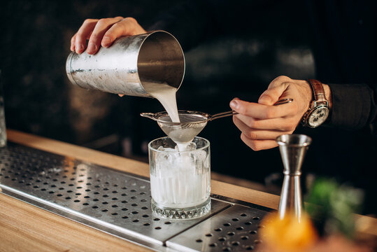 Barista preparing cocktail with bar equipment and pours milk in cocktail