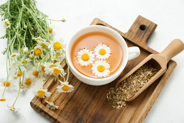 Cup of hot chamomile tea on light background