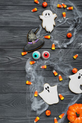 Composition with tasty Halloween candy corns and cookies on dark wooden background
