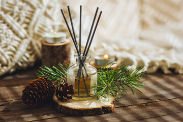 Aroma diffuser, burning candle, pine essential oil and perfume on wooden table. Cozy home decor,...