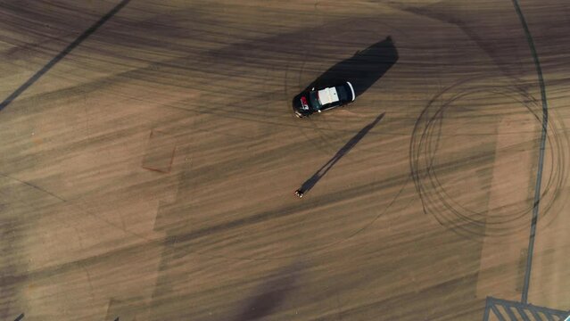 Epic high shot of cop car doing donuts around man