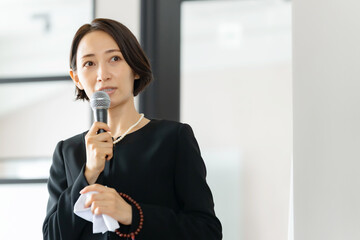 挨拶する喪主・葬式・告別式・女性