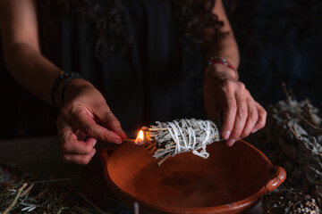 Approach to a hand lighting an incense burner, Halloween, spiritual beliefs, white magic - obrazy, fototapety, plakaty