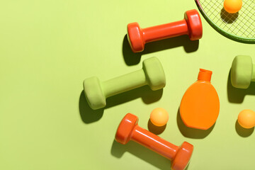 Composition with bottle of sunscreen cream, dumbbells and ping pong balls on color background