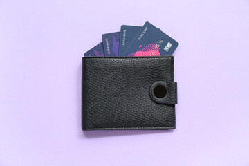 Obraz premium Black leather wallet with credit cards on lilac background