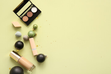 Composition with decorative cosmetics and Christmas balls on light yellow background