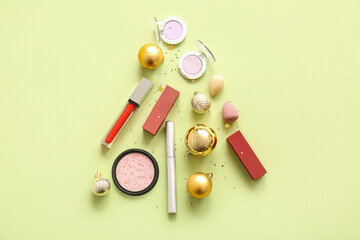 Christmas tree made of makeup cosmetics and golden balls on light yellow background