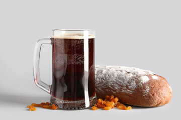 Mug of tasty kvass, bread and raisins on grey background