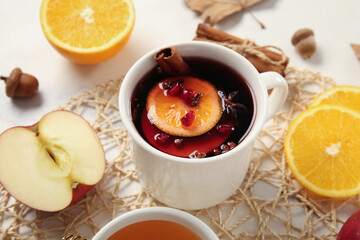 Cup of hot mulled wine with orange, pomegranate and apple on white background