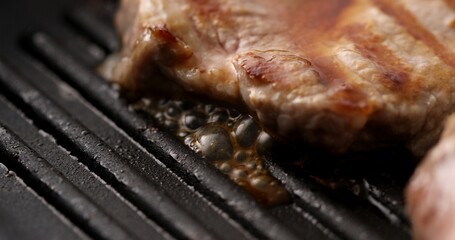 Pieces of Delicious juicy meat are fried on a grill pan with steam and bubbles of fat. Cooking steaks. Preparing food in the kitchen. Close-up dolly shot.