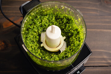 Freshly Mixed Pesto in a Small Food Processor: Italian pesto sauce ingredients including basil and olive oil blended in a mini-prep