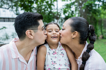 Fototapeta premium Daughter Receives Kiss on the Cheek from Mom and Dad, Pure Love