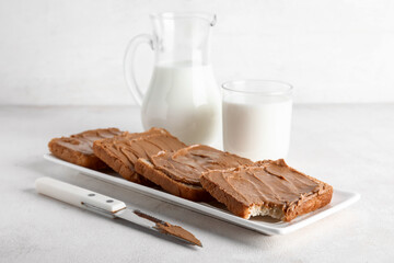 Plate of toasts with peanut butter and glass of milk on white background