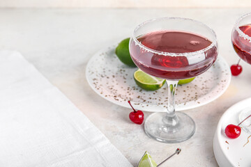Glass of Cosmopolitan cocktail with cherries and lime on white background