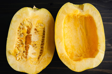 Sliced Spaghetti Squash with One Side Seeded: Halved spaghetti squash with and without seeds close-up on a wooden table