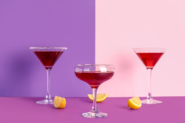 Glasses of Cosmopolitan cocktail with lemon on colorful background