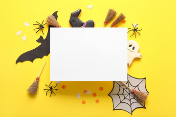 Halloween composition with black greeting card, brooms and decor on yellow background