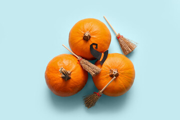 Halloween composition with pumpkins, brooms and witch hat on blue background