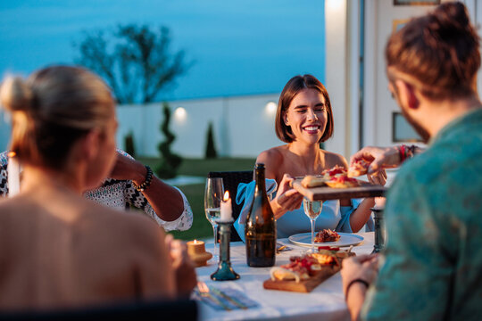 Woman serving food to her friends during pool dinner party