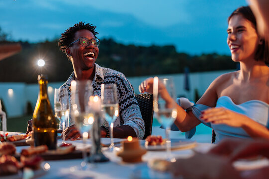Friends laughing during evening poolside dinner