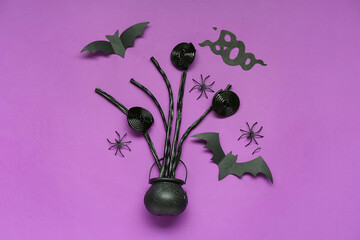 Halloween composition with sweet candies, cauldron and word BOO on purple background