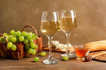 Glasses of exquisite wine with honey and grapes on brown background