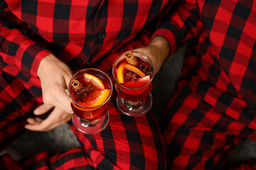 Young couple with glasses of mulled wine at home on Christmas eve, closeup