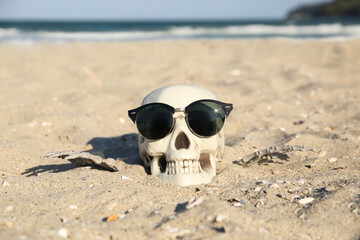 Obraz premium Skull for Halloween with stylish sunglasses and skeleton hands on beach