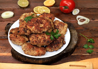 Homemade cutlets with onions, tomatoes and garlic, spicy herbs on a wooden background, delicious natural food, advertising for the menu, cafe-restaurant, top view, place for text, rustic style,
