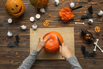 Woman carving Halloween pumpkin at wooden table