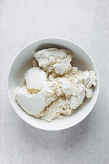 Strained Greek yogurt in a white ceramic bowl, process of making Greek yogurt, strained thick yogurt in white mixing bowl
