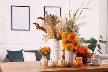 Beautiful autumn composition with bright orange flowers, pumpkins and burning candles on wooden table in room - Powered by Adobe