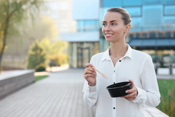 Smiling businesswoman with lunch box outdoors. Space for text