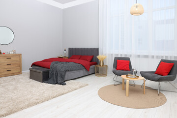 Stylish bedroom with comfortable bed, armchairs and table. Interior design