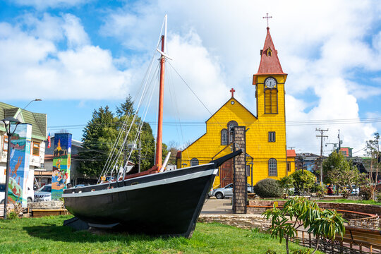 Monumento a La lancha velera Chilota y de fondo Iglesia San Miguel Arc&aacute;ngel, en Plaza de Armas, ciudad de Calbuco, Chile.
