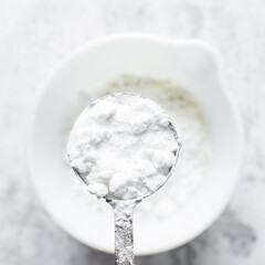 Powdered sugar in a measuring spoon, measuring confectioners sugar for baking, a silver measuring spoon with icing sugar
