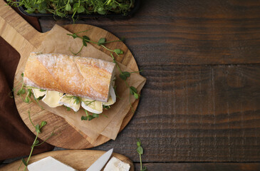 Tasty brie cheese sandwich on wooden table, flat lay. Space for text