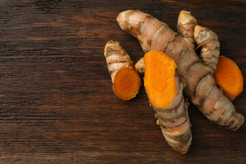 Fresh turmeric roots on wooden table, flat lay. Space for text