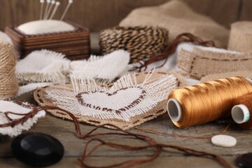 Pieces of burlap fabric with different stitches and sewing tools on wooden table - obrazy, fototapety, plakaty