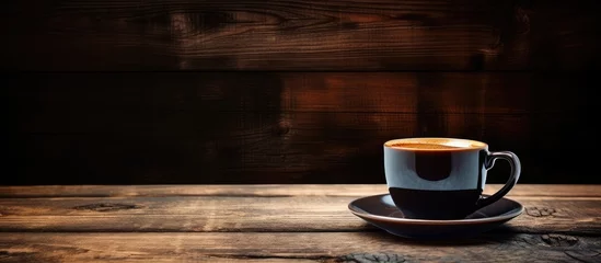 Fotobehang Coffee cup and saucer on wooden table with dark background © TheWaterMeloonProjec