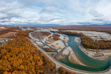 Autumn aerial view of the river valley. Top view of the river and forest. Yellow larch trees. Beautiful northern nature. Travel to Siberia and the Russian Far East. Ola river, Magadan Region, Russia.