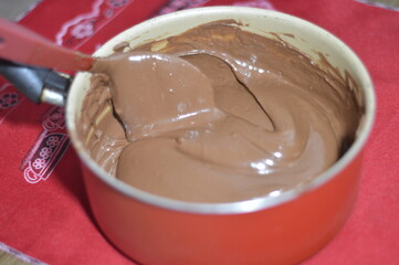 Creamy chocolate in the pan with drops falling from the spoon