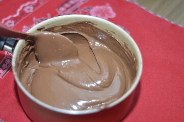 Creamy chocolate in the pan with drops falling from the spoon