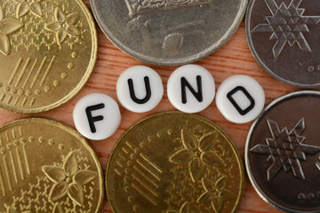 Coins and alphabet beads with text FUND. a "fund" refers to a pool of money or capital that is collected from multiple investors or contributors for a specific purpose