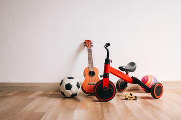 Children room with tricyle, ukulele guitar and balls on wooden floor.  Kids toys. 