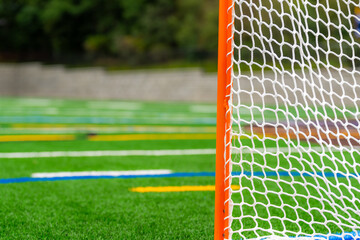 Photo of a lacrosse goal on a empty green synthetic turf field.	