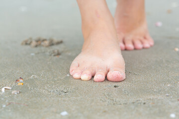Young woman's feet walking on the beach on vacation