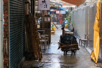 Hard rain falls on abandoned cardboard collection cart in alley