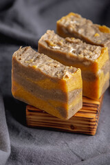 Pieces of natural handmade soap on a wooden soap dish and the dark background